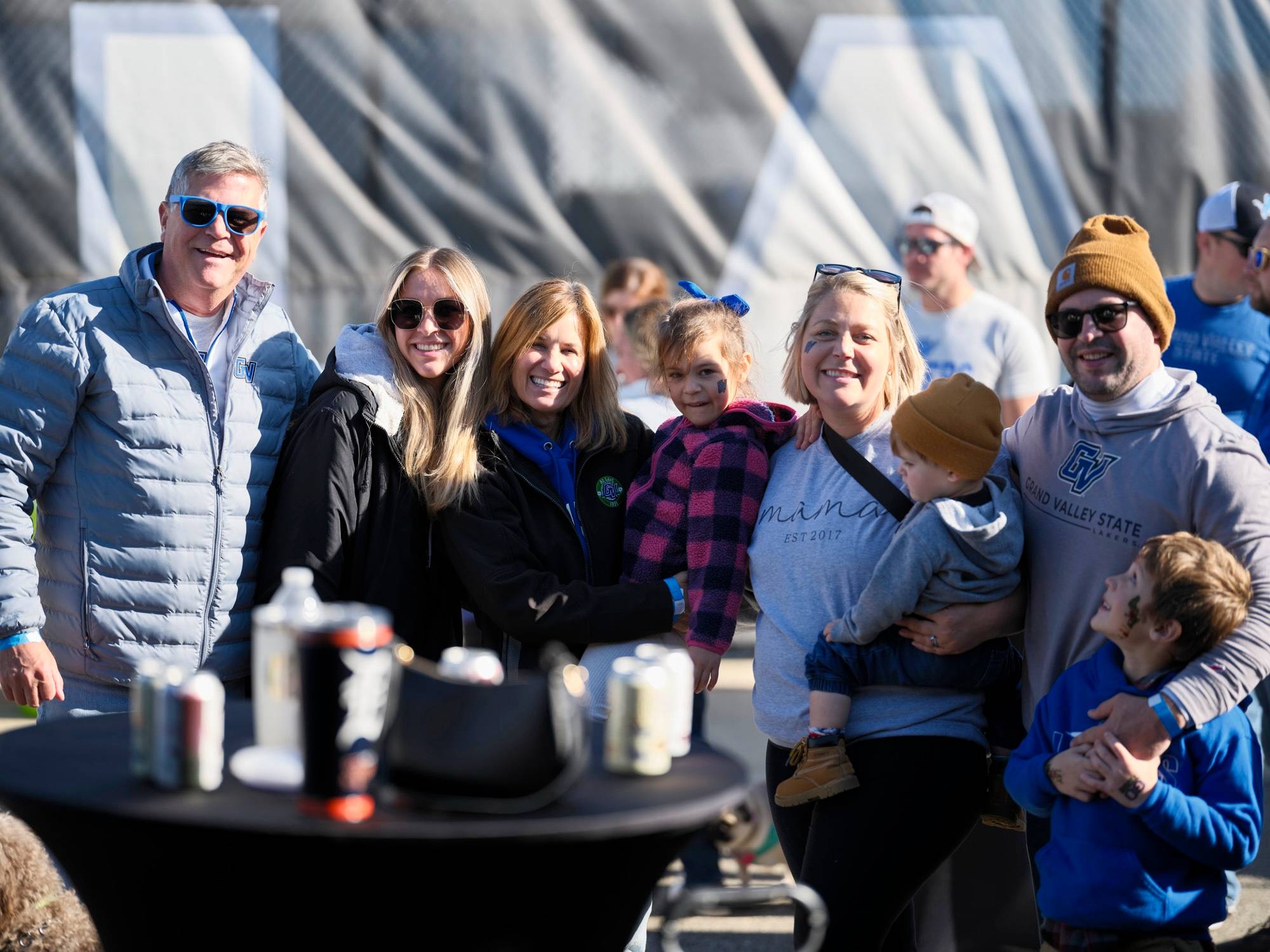 A group of alumni smile with President Mantella during a Homecoming tailgate wearing GV gear